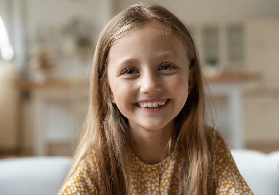 Girl sitting on a couch with a bright, cheerful smile on her face
