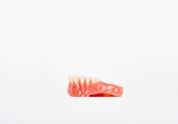 Close up of a dentor on a white background, with a red and white color scheme