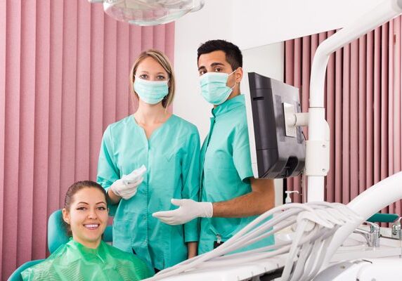Woman sitting in a dentist's chair with two men standing next to her