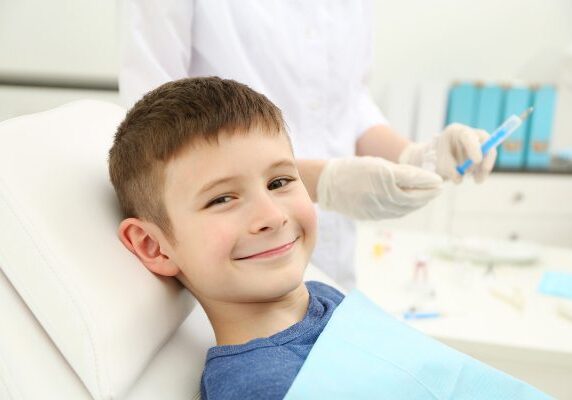 Boy sitting in a dentist's chair with a big smile on his face