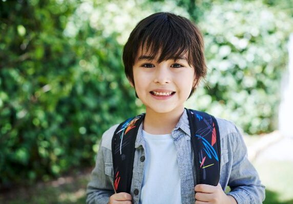 Boy with a backpack standing in front of a tree
